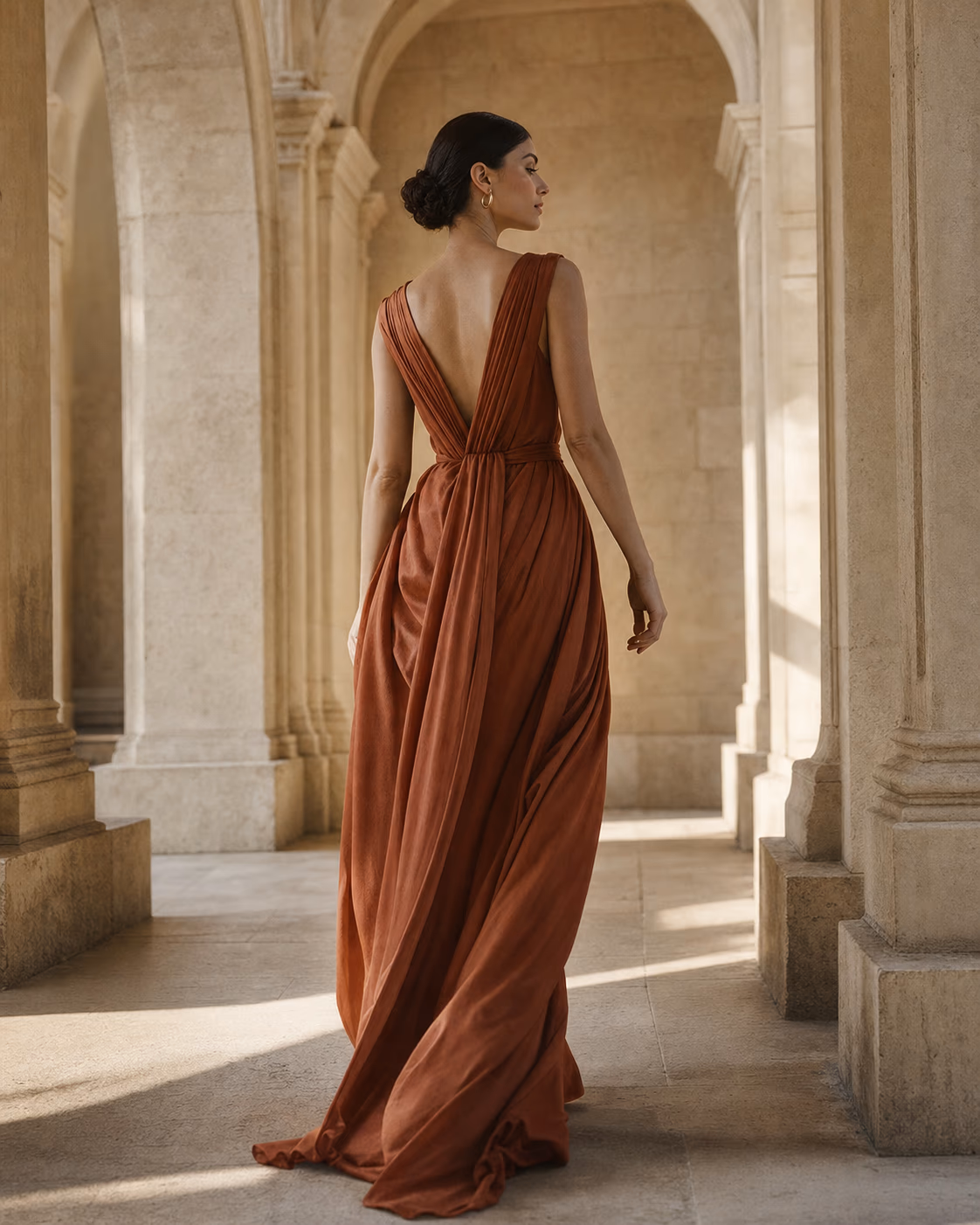 Editorial portrait of a woman in a rust dress among classical stone arches